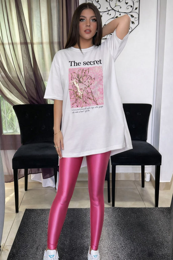 Woman wearing a white oversized t-shirt with a graphic design and pink leggings in an indoor setting.