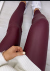 Maroon leggings worn with white sneakers on a light wooden floor.