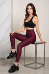 Woman wearing a black sports bra and maroon leggings sitting on a stool.