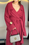 Person wearing a red coat holding a Gucci handbag indoors.